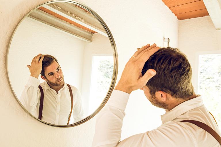 Man grooming his hair in front of a mirror.