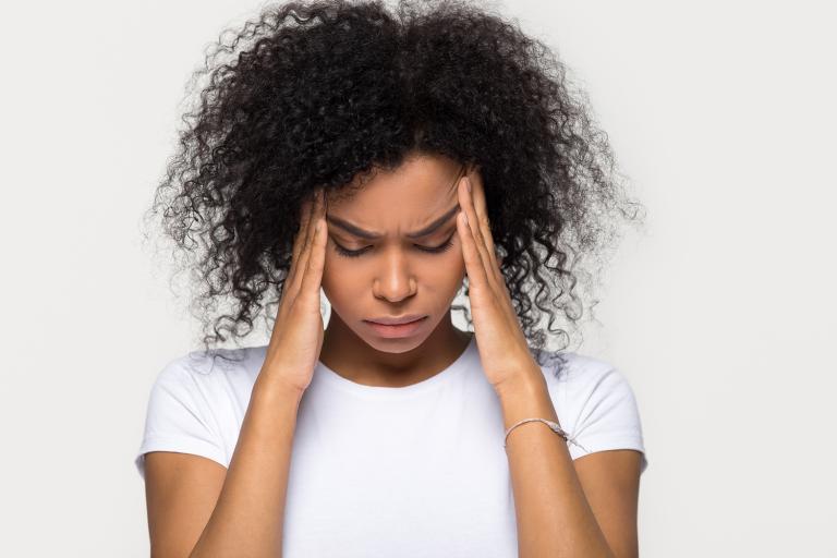 a woman with a serious headache rubbing her temples